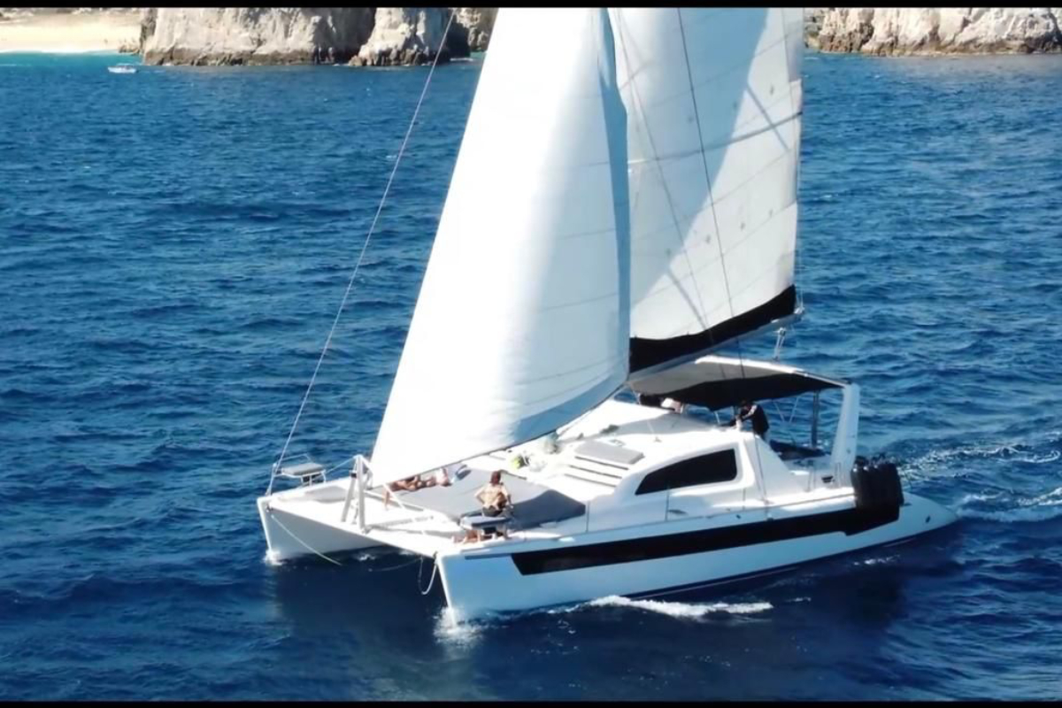 Cabo catamaran sailing under full sail off the Los Cabos coastline