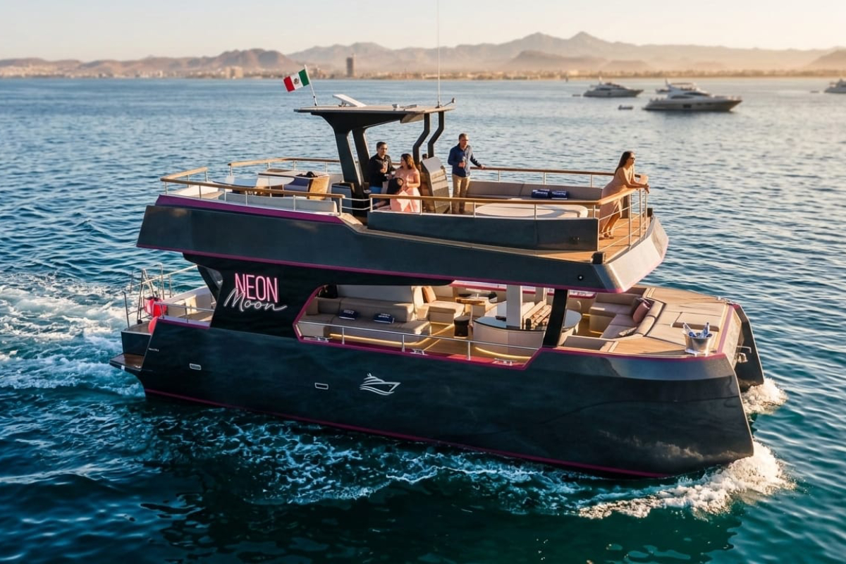 Guests relaxing on both levels of the Neon Moon Cabo catamaran at golden hour
